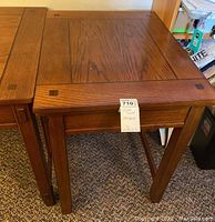 Photo showing two stacked wood side tables from Ashley Furniture with visible scratches on top surfaces.