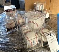Overview photo showing multiple signed baseballs in clear acrylic display cases arranged on wrapped surface.