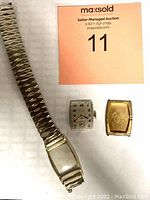 Overall view of watch band, rectangular watch dial, and gold filled rectangular watch case separated and laid out