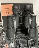Black textured Sears binoculars with neck strap viewed from side, showing structure and lens barrels.