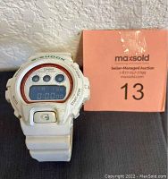 Front view of the white Casio G-Shock digital watch showing the display and buttons around the face, with some dirt visible on the bezel and strap.