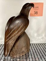 Front view of the hand carved wooden bald eagle sculpture showing detailed carving of the wing and head with attached perch.
