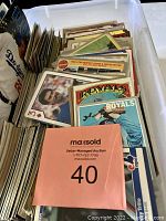 Photo of a large plastic bin filled with assorted baseball trading cards, some cards are visible displaying teams like Royals and Dodgers.