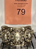 Front view of the wide silver cuff bracelet showing detailed raised circular elements and beaded border decoration.