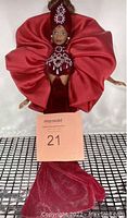 Full body photo showing Barbie in red gown with large ruffled collar and jeweled decorations.