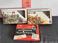 Two boxed sets of toy soldiers and a vintage Autobridge game box arranged together.