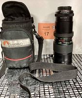 Vivitar zoom telephoto lens standing next to Lowepro camera bag on display shelf.