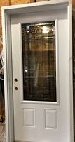 Front view of white steel exterior door and frame with decorative glass insert