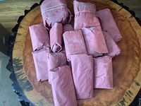 Seventeen butcher-wrapped packages of beef on a wooden round surface
