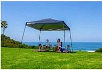 Galvanized steel frame folding sun shelter set up on grassy area by the sea with midnight blue canopy.
