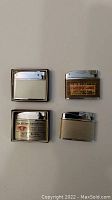 Four flat vintage advertising lighters laid out on flat surface, two in original boxes.