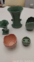Five pieces of Abingdon pottery including three vases, a planter, and a candle holder on a white surface.
