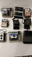 Full view of the 9 cameras showing variety and style including instant and folding cameras.