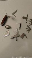 Overview of 9 various cutting utensils including multi-tool pocket knives, a vintage hobo tool with fork and spoon, and other small cutting implements.