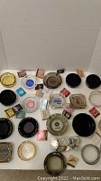 Top-down photo showing a collection of 20 casino ashtrays of different styles and numerous vintage matchbooks arranged around them.