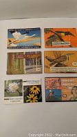 Photo showing the six vintage nature books spread out, including Birds of North America, Tropical Birds, Trees, Wildflowers, and Indians. Teacards accompany the books, some missing from Birds of North America and Wildflowers.