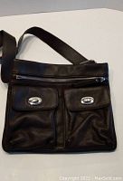 Brown Danier leather shoulder purse with front two flap pockets and silver-tone turn-locks on white background