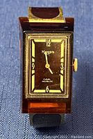 Front view of rectangular Mappin's watch with black face, gold numerals, and cracked brown band.