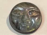 Front view of round carved labradorite moon face pendant with silver bezel setting.