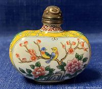 Front view showing detailed enamel artwork of multicolored birds on a blossoming branch with yellow background.