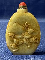 Front side of small carved jade snuff bottle showing two children playing.