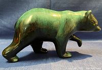 Side view of the green and black glazed grizzly bear sculpture showing detailed glaze texture and walking pose.