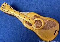 Top view of handcrafted wooden guitar puzzle box showing detailed wooden puzzle pieces forming the guitar shape.