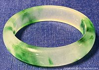 Close-up side angle showing the thickness, polish, and color variation in the jade bangle.