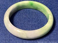 Jade bangle showing side angle, polished with gradient lavender and green hues.