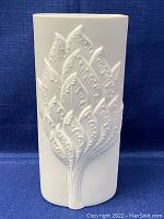 Front view of white bisque porcelain vase with raised leaf pattern embossing
