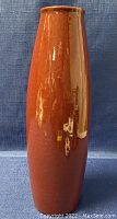 Full view of the tall red-brown glazed ceramic vase showing its cylindrical shape