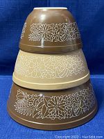 Stacked view of three Pyrex Woodland nesting bowls showing exterior floral design and colors