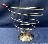 Full side view of the spiral stainless steel fruit basket showing its modern spiral form and red accents on the top and base.
