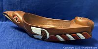 Side profile showing bowl shaped like canoe with bird head at one end and red and white geometric painted patterns on side