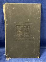 Front side of the wooden book cover showing carved Chinese characters in a square pattern with decorative border.