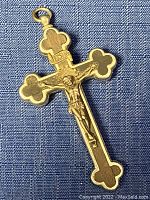 Front view of metal religious cross showing Jesus crucifix figure with wood inlay on blue fabric background.