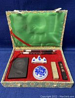 Top-down view of the vintage Chinese calligraphy set in open fabric-covered case, showing porcelain ink holder, carved soapstone ink stone, seal stone, black ink stick, porcelain brush rest, and one calligraphy brush.