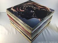 Stack of 48 assorted vinyl LP record albums showing edges and spines, various colors and conditions.