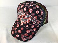 Front and angled front views showing black baseball cap with red, white Baby Milo and peace motifs. 'Baby Milo' embroidered text with star detail on the front.
