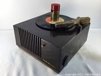 View of the RCA Victor 9EY3 black vintage record player with red and brass tonearm and a 45 rpm record on the turntable.