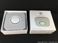 Photo of the alarm device in white box showing the device inside packaging.