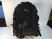 Front view of black Lowepro Nature Trekker AW camera backpack with visible logo, padded straps and attached tags.