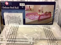Box and main part of DOM Deluxe Bed Rail in white, new and sealed in plastic, includes packaging showing installation and use.