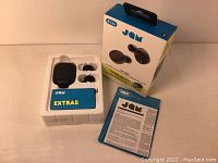 Photo showing the JAM Live Loud box, earbuds inside black charging case, extras box, and instruction manual.