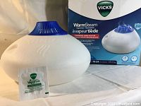 Vicks Warm Steam Vaporizer with VapoPads and the retail box shown on the table.