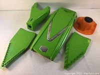 Green Borner V-Slicer mandolin with three green blades and orange hand guard against white background.