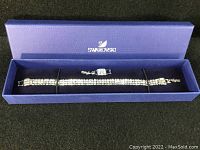Swarovski three row clear crystal bracelet placed inside a blue Swarovski gift box to show packaging and overall design
