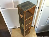 Full view of the handmade wooden shelving unit with decorative animal and tree carvings on the side.