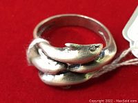 Close-up side view of the sterling silver dolphin ring, showing detailed dolphin heads and marking.