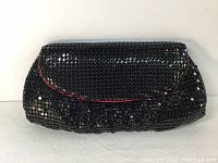 Front view of vintage black beaded purse showing red velvet trim on flap